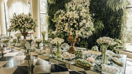 Elegant wedding dessert table with floral centerpieces and assorted sweets, showcasing a luxurious and beautifully styled wedding reception setup.