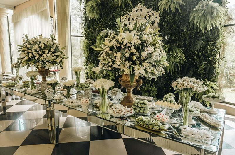 Elegant wedding dessert table with floral centerpieces and assorted sweets, showcasing a luxurious and beautifully styled wedding reception setup.